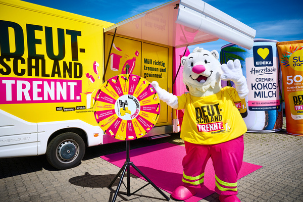 Quelle M�lltrennung wirkt. Das Bild zeigt den Infotruck mit dem Schriftzug Deutschland trennt, im Vordergrund steht das gelb/pinkfarbene Gl�cksrad, rechts vom Gl�cksrad steht der Trennb�r, rechts im Hintergrund stehen zwei Gro�verpackungen 